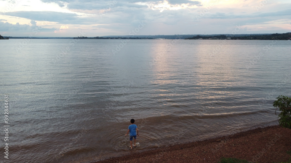Criança brincando à margem do lago Paranoá.