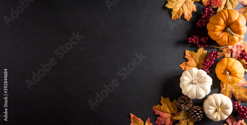 Thanksgiving background decoration from dry leaves,red berries and pumpkin on blackboard background. Flat lay, top view for Autumn, fall, Thanksgiving concept.