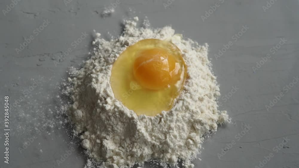 Breaking eggs on flour on grey background. Breaking eggs on flour on grey background.