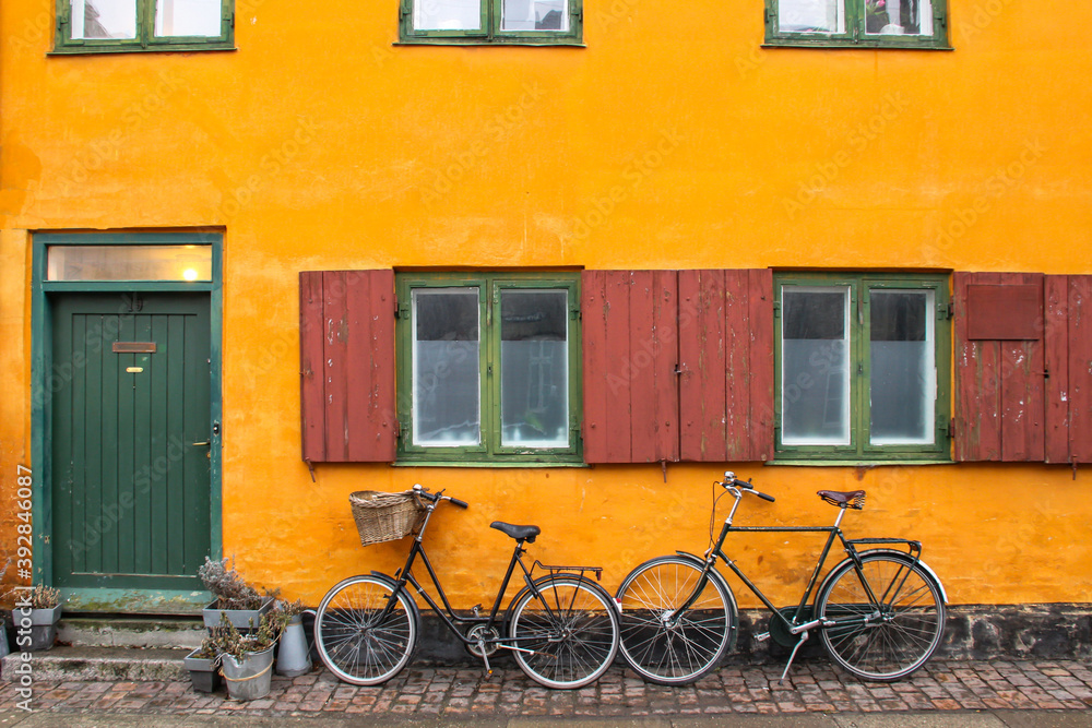 Bicycles in front of an yellow orange house facade in Nyboder,historic row house district of former Naval barracks in Copenhagen, Denmark.Picturesque European city of Copenhagen.Royal Danish Navy