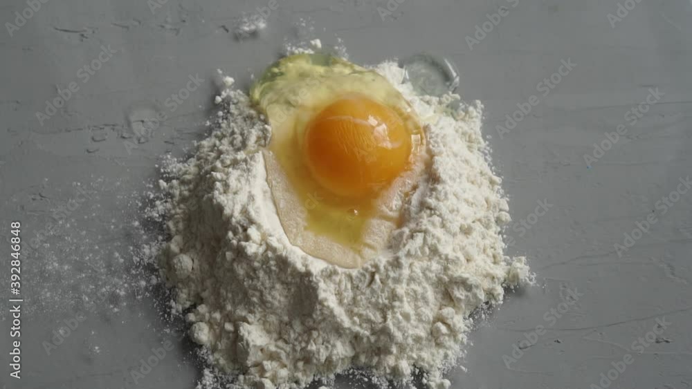 Breaking egg on flour on grey background. Breaking egg on flour on grey background.