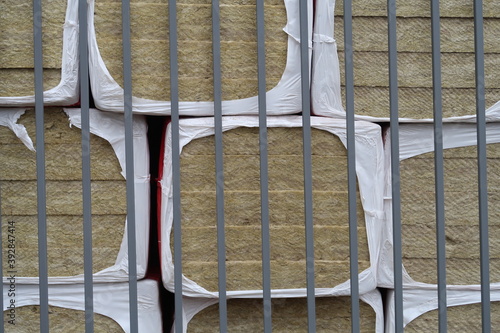 Rolls of construction insulation folded behind a metal fence photo