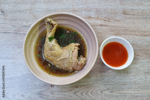 boiled chicken thigh and leg with herb brown soup in bowl dipping spicy chili sauce cup 