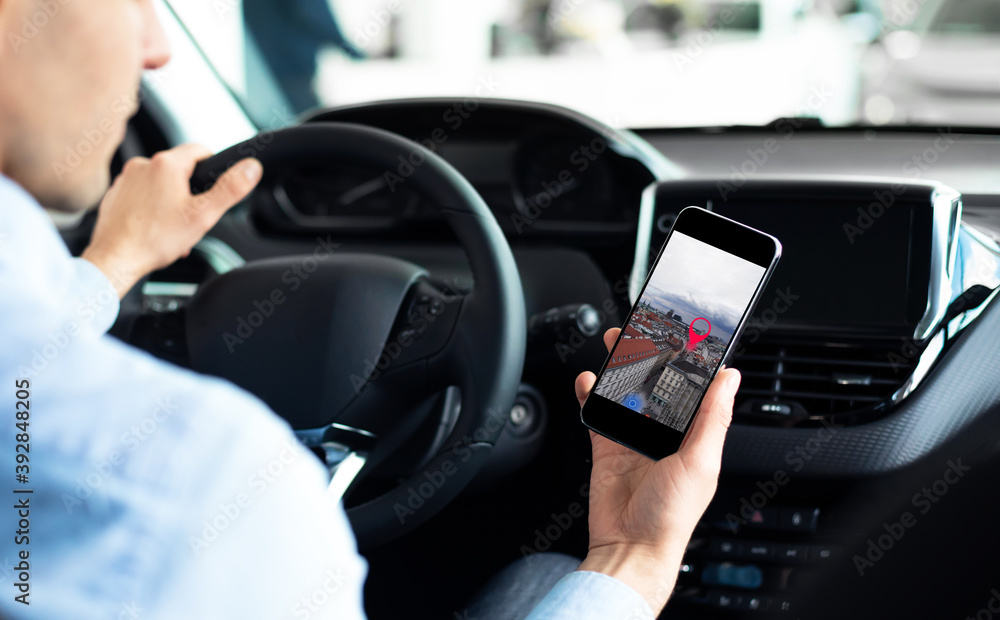 Man Driving Car Using Phone With Mobile Navigation Application