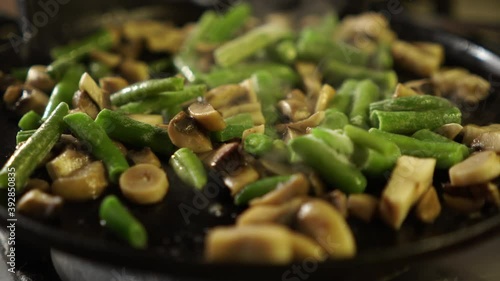 Close-up cooking mushrooms, asparagus, in a frying pan. Home kitchen, indoors.