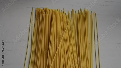 Raw spaghetti in hand on grey background. Slow motion.