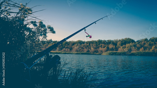 Fishing rod with a bell on the lake in the autumn.