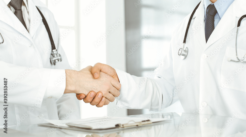 Two doctors are shaking hands as agreement about patient's treatment, close-up. Medical help, medicine concept Two doctors are shaking hands as agreement about patient's treatment, close-up. Medical help, medicine concept
