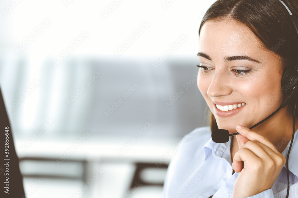 Brunette female customer service representative in a headset is consulting clients online. Call center and business people concept Brunette female customer service representative in a headset is consulting clients online. Call center and business people concept