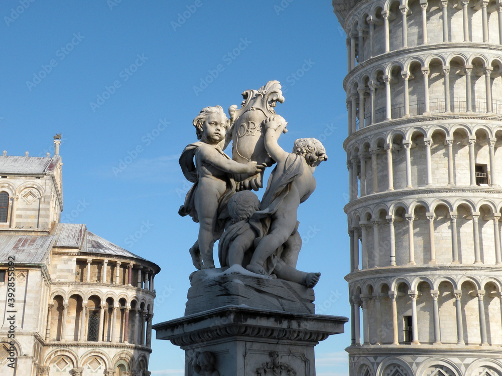 The Putti fountain in Piazza dei Miracoli in Pisa. On the right the Leaning Tower of Pisa and on the left the Cathedral of Pisa.    