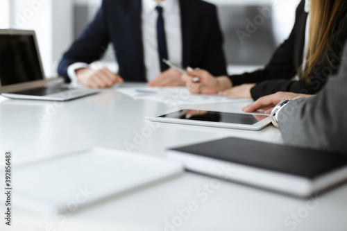 Unknown businessmen and woman sitting, working and discussing questions at meeting in modern office, close-up