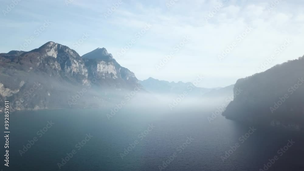 Panoramic shot of low-hanging fog between mountain ranges above the water surface of a crystal blue mountain lake Panoramic shot of low-hanging fog between mountain ranges above the water surface of a crystal blue mountain lake