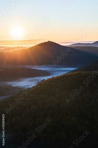 Berg bei Sonnenaufgang mit Nebel im Tal im Wald