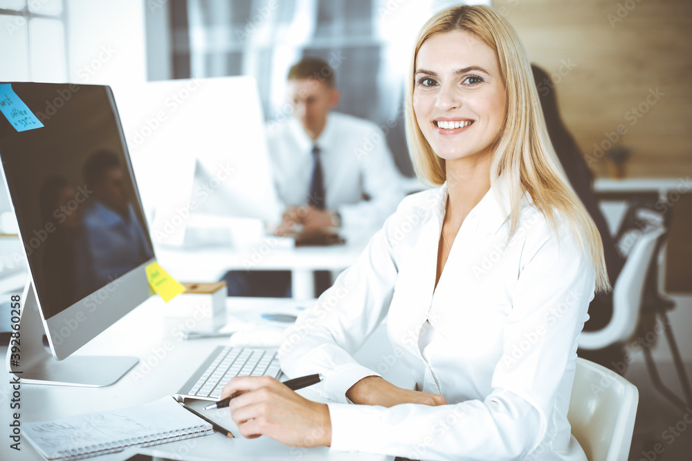 Business woman using computer at workplace in modern office. Secretary or female lawyer smiling and looks happy. Working for pleasure and success Business woman using computer at workplace in modern office. Secretary or female lawyer smiling and looks happy. Working for pleasure and success