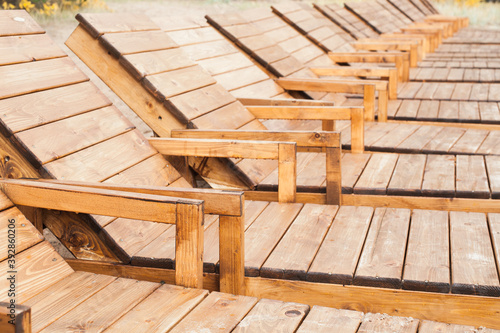 Empty wooden sun lounges stand in a row © evannovostro