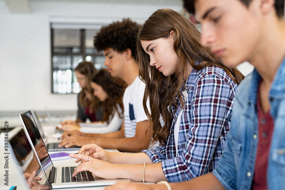 Fototapeta Group of high school students using laptop in classroom