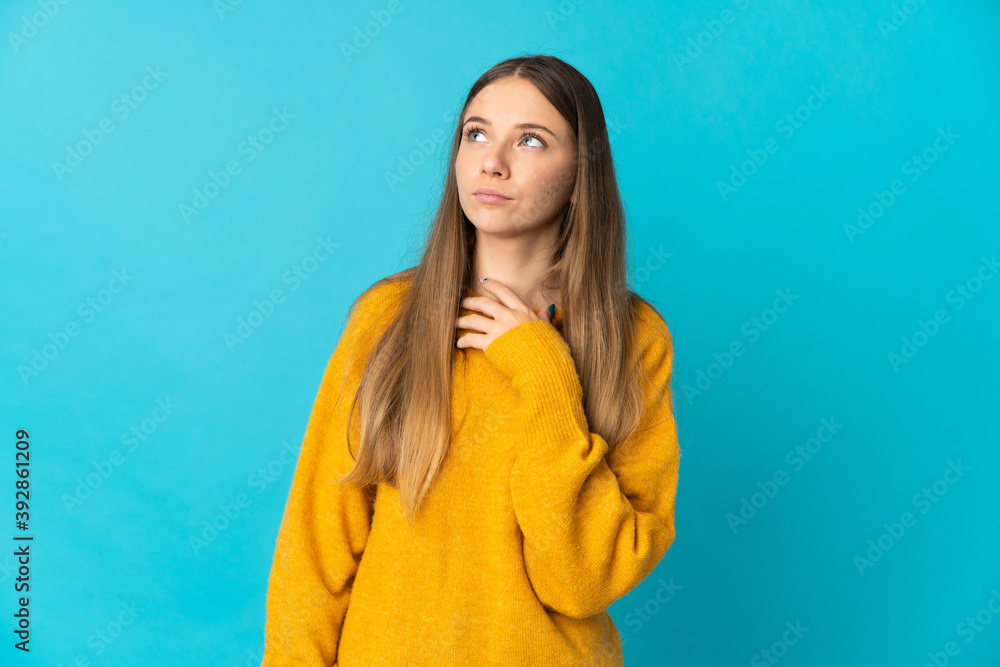 Fototapeta premium Young Lithuanian woman isolated on blue background looking up while smiling