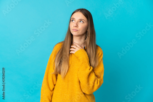 Young Lithuanian woman isolated on blue background looking up while smiling