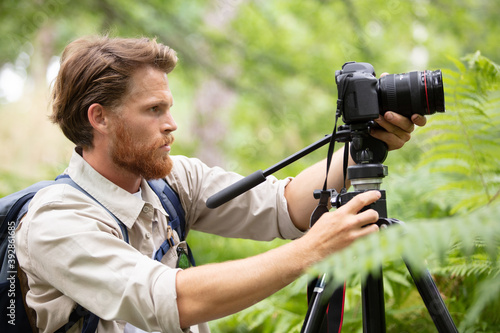 photographer looking at screen of dslr camera on tripod