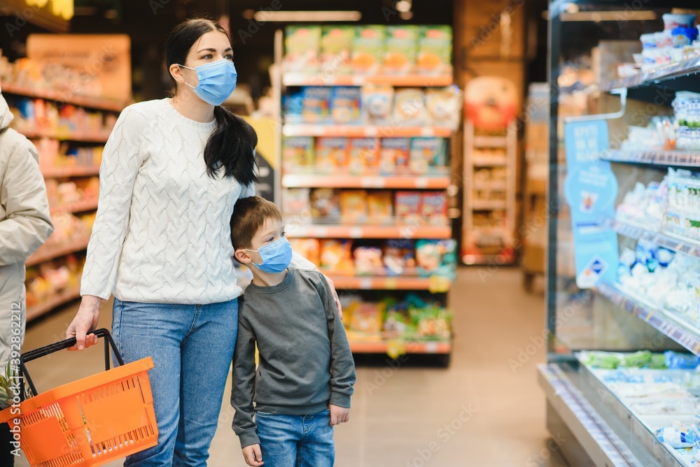 Young woman and her little son wearing protective face mask shop a food at a supermarket during the coronavirus epidemic or flu outbreak