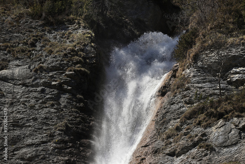 Water Splashing down waterfall lit by sunlight with black background showing freshness.