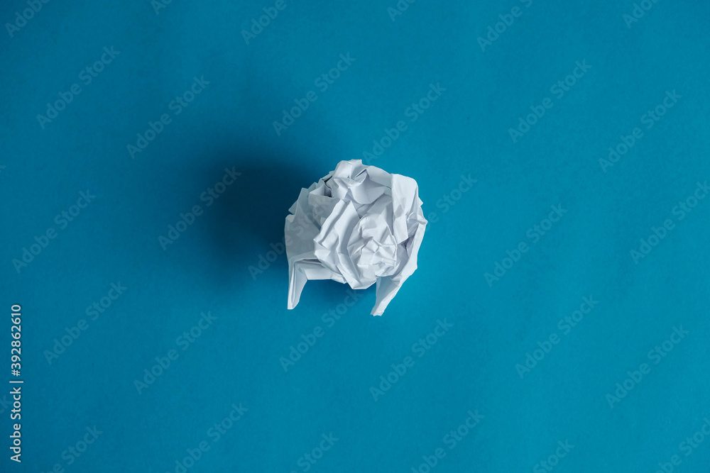 Crumpled paper ball on a blue background. Minimalist concept. Top view. Copy, empty space for text Crumpled paper ball on a blue background. Minimalist concept. Top view. Copy, empty space for text