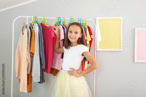 Little cute girl chooses clothes in dressing room