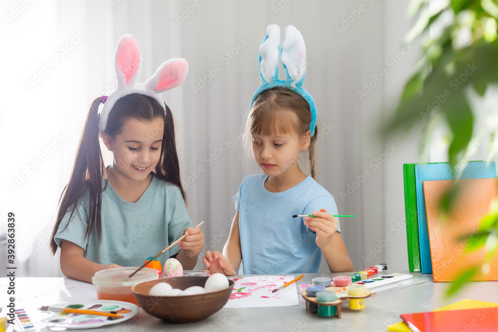 Happy easter. Two sisters painting Easter eggs. Happy family children preparing for Easter. Cute little child girl wearing bunny ears on Easter day.