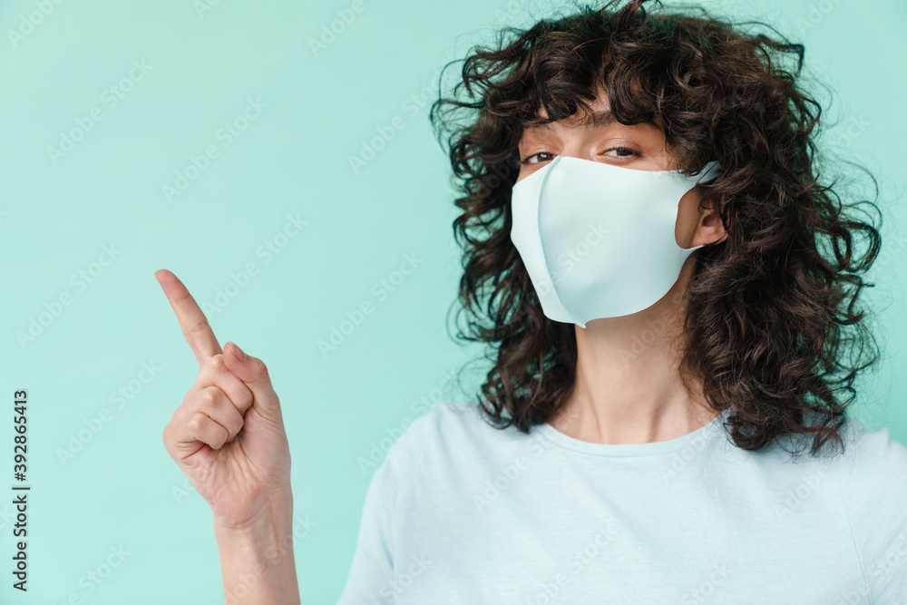 Caucasian nice curly girl in face mask pointing finger aside