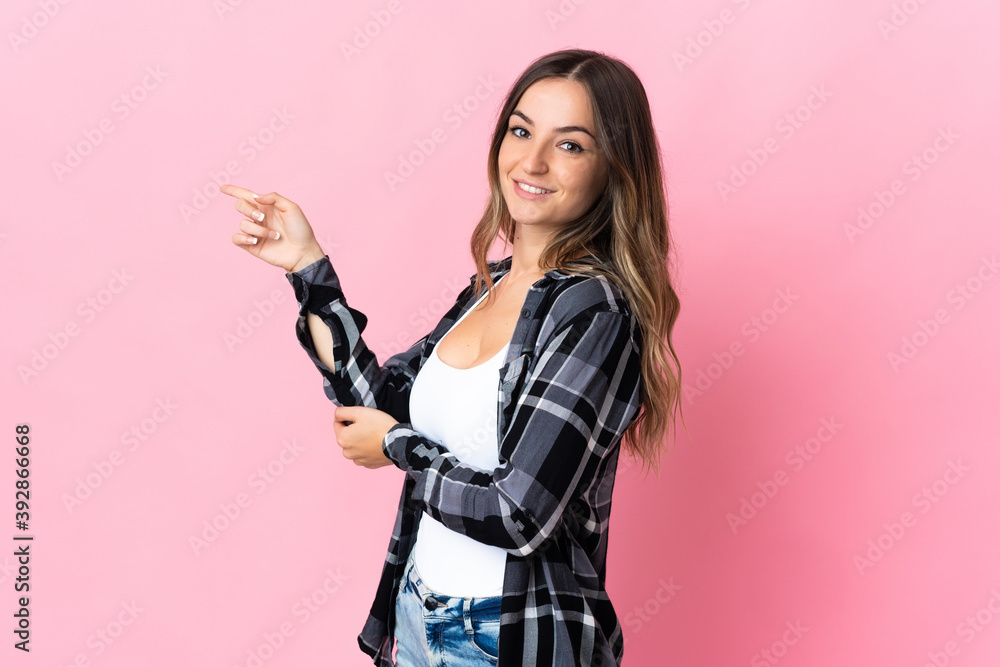 Young Romanian woman isolated on pink background pointing finger to the side Young Romanian woman isolated on pink background pointing finger to the side