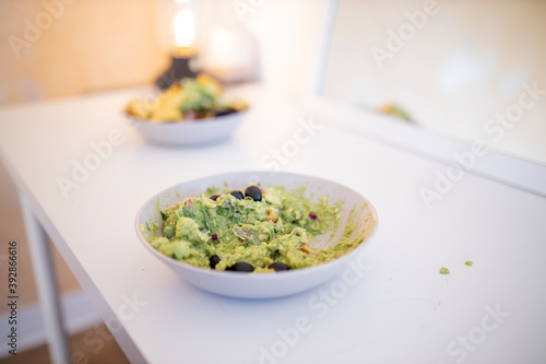 Bowl of guacamole sauce with olives on a white table