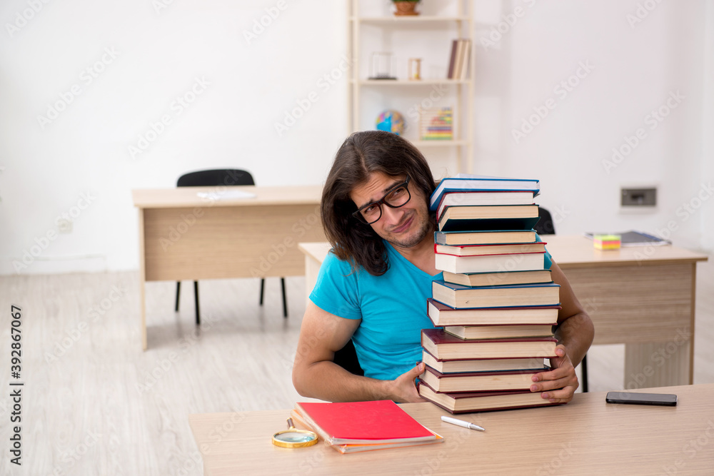 Young male student and a lot of books in the class Young male student and a lot of books in the class