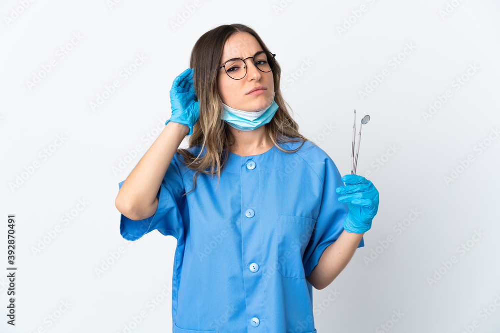 Woman Romanian dentist holding tools over isolated on pink background having doubts Woman Romanian dentist holding tools over isolated on pink background having doubts