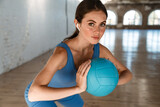 Beautiful brunette sportswoman in earphones working out with ball