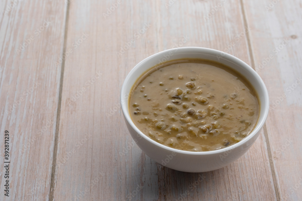 Mung beans porridge (bubur kacang hijau) is a Malaysian traditional dish usually eat as starter or desert. Made from mung beans, coconut milk & palm sugar. Isolated over wooden background. Mung beans porridge (bubur kacang hijau) is a Malaysian traditional dish usually eat as starter or desert. Made from mung beans, coconut milk & palm sugar. Isolated over wooden background.