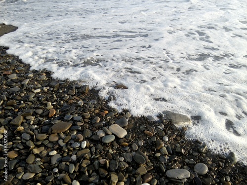 The foamy wave runs onto the rocky shore. beach, foamy wave, ocean, pebbles, sea, stone