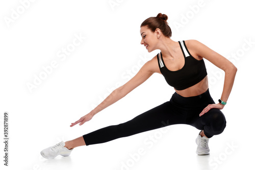 Fit strong fitness woman in sportswear stretching legs on white isolated background. Female sport instructor doing physical exercise