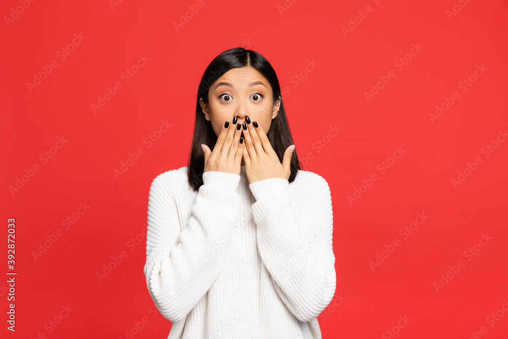 shocked asian woman covering mouth with hands isolated on red shocked asian woman covering mouth with hands isolated on red