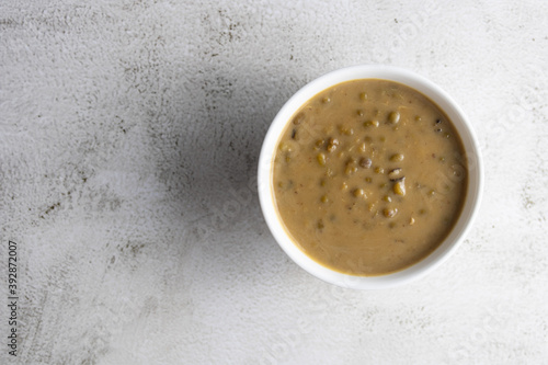 Mung beans porridge (bubur kacang hijau) is a Malaysian traditional dish usually eat as starter or desert. Made from mung beans, coconut milk & palm sugar. Isolated over wooden background.