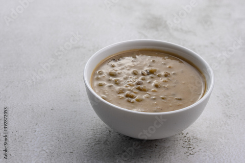 Mung beans porridge (bubur kacang hijau) is a Malaysian traditional dish usually eat as starter or desert. Made from mung beans, coconut milk & palm sugar. Isolated over wooden background.