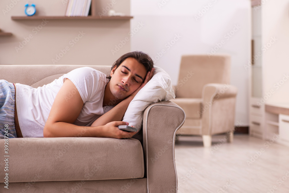 Young lazy man in oversleeping concept at home Young lazy man in oversleeping concept at home