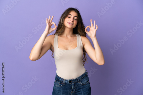 Young caucasian woman isolated on purple background in zen pose