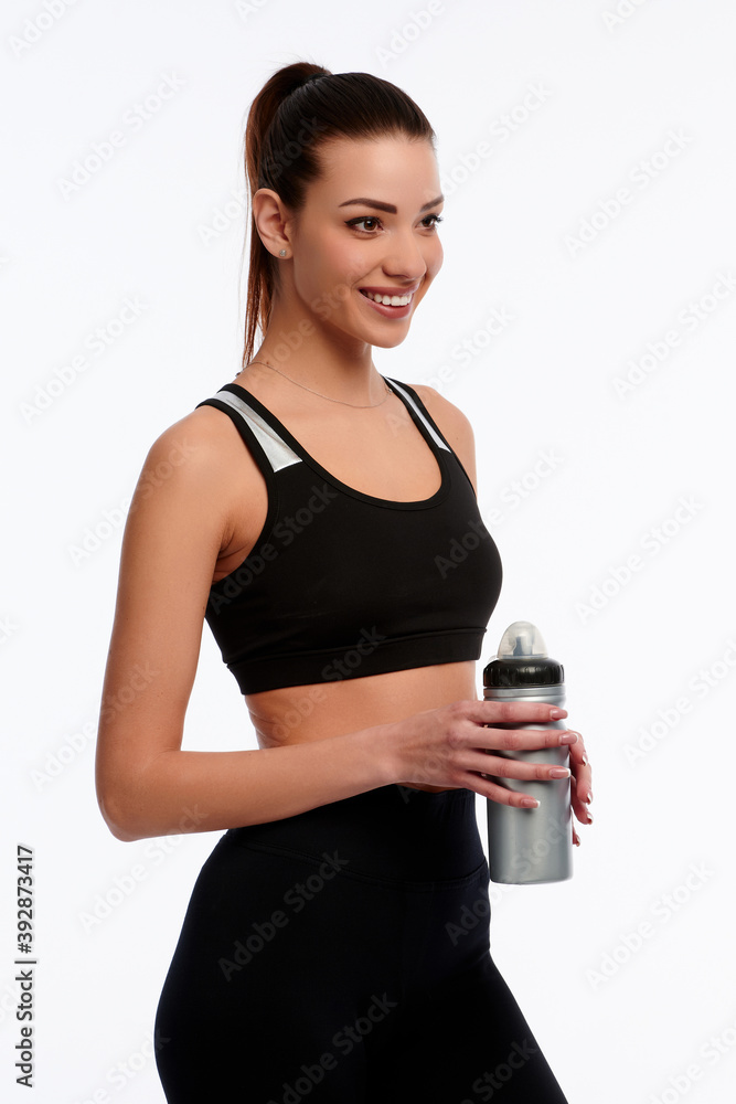Smiling caucasian fitness instructor holding plastic bottle of water on white isolated background. Sporty woman, healthcare concept Smiling caucasian fitness instructor holding plastic bottle of water on white isolated background. Sporty woman, healthcare concept