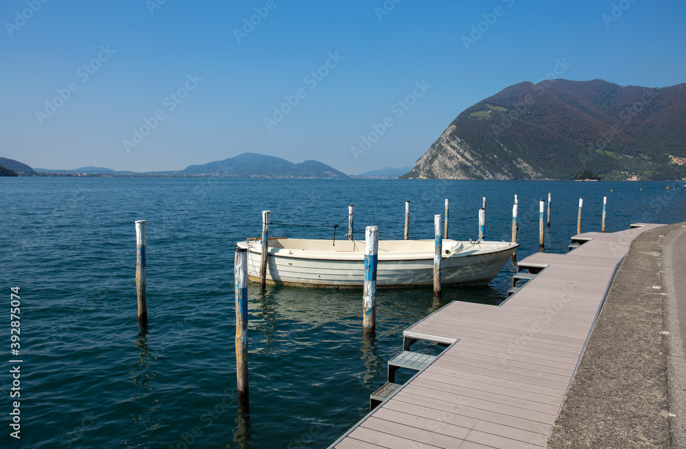 Isolated white boat moored at Monte Isola, Iseo Lake, Brescia province, Lombardy, Italy.