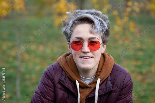 Young woman with stylish short hair, dressed in a gender neutral style.  New femininity. Style Element - Red Sunglasses © Volha