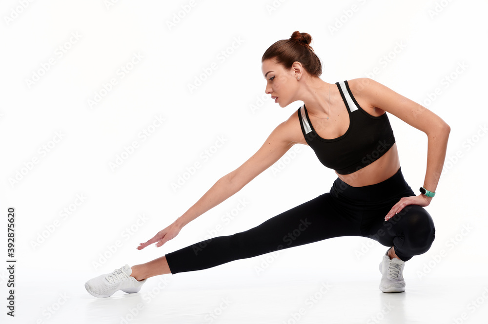 Smiling sports woman stretching legs while isolated on a white background Smiling sports woman stretching legs while isolated on a white background
