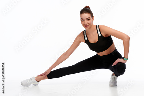 Slim and strong caucasian woman doing stretching exercise before physical training, white isolated background