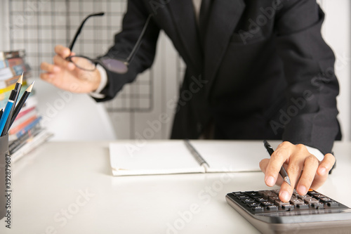 businessman hand using calculator Calculating bonus Or other compensation  to employees to increase productivity. on desk.Selective Focus