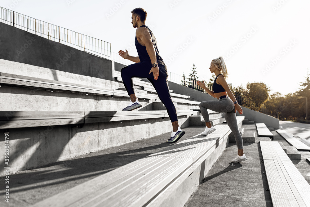 We work on the stairs. Sporty young couple in sportswear running together on stairs, outdoors