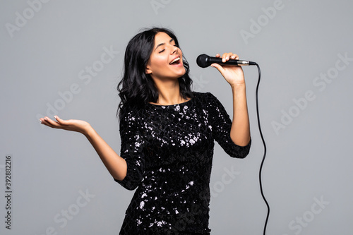 Photos Beautiful brunette woman singing to microphone isolated on gray background